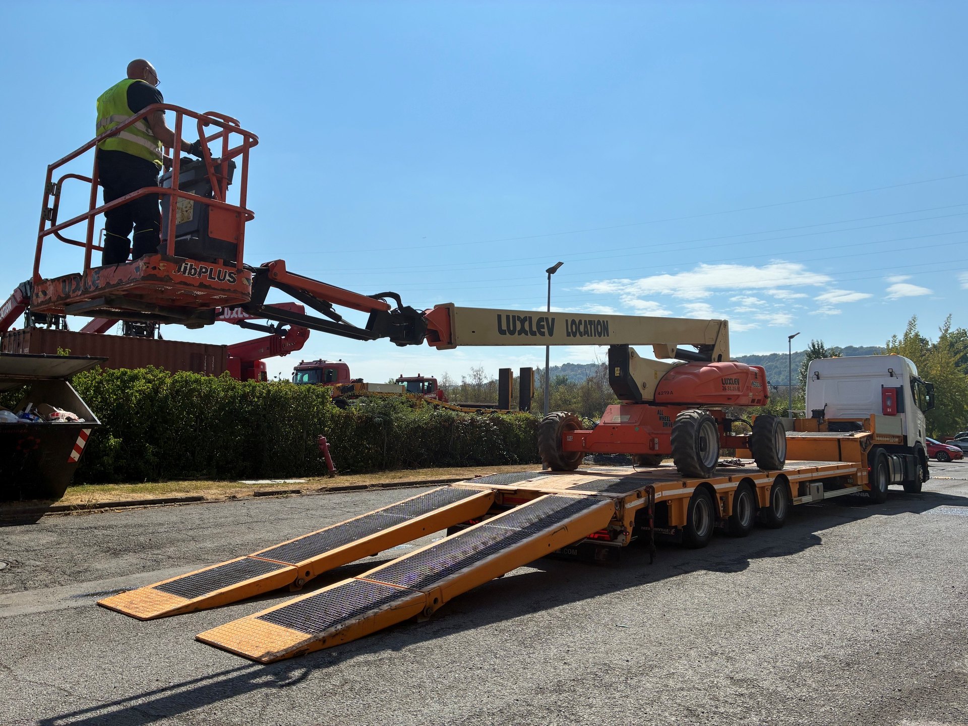 Chargement d'une nacelle télescopique LUXLEV sur le porte-engins de l'entreprise, rampes déployées